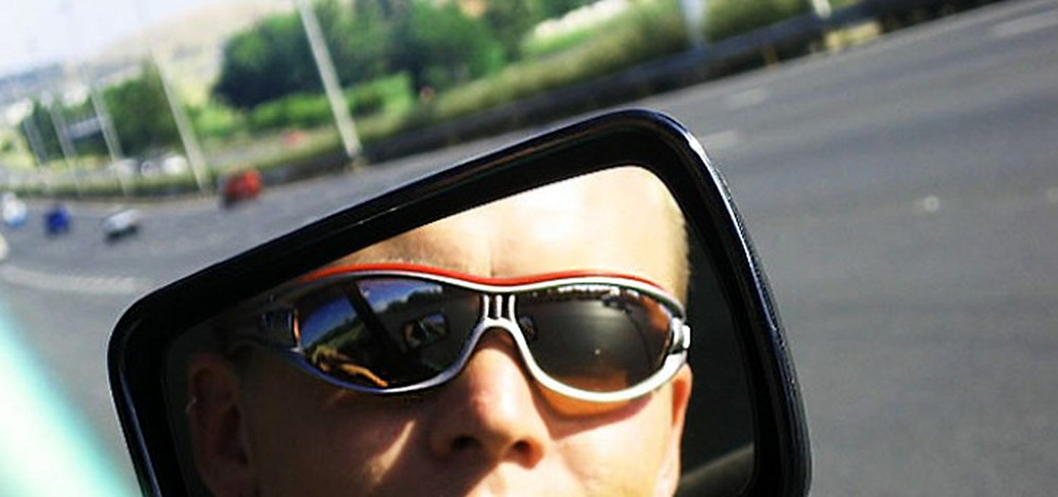 Driver in Sunglasses Reflected in Car Wing Mirror