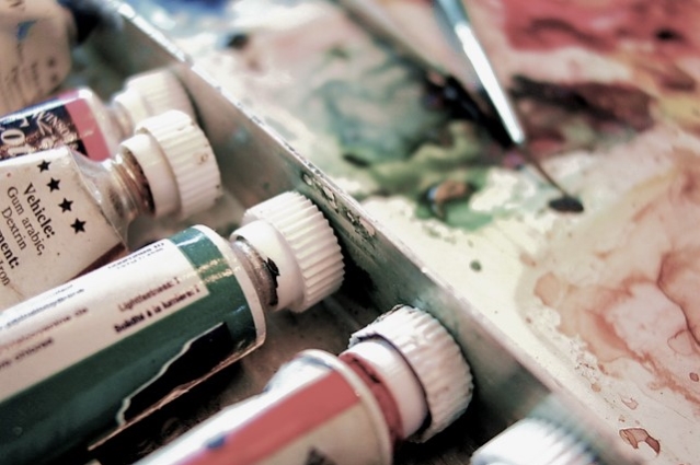 Close up photo of artists paints, canvas and thin paintbrush