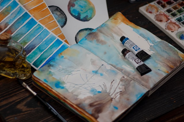 sketchbook with watercolour paintings and tubes of watercolour paint