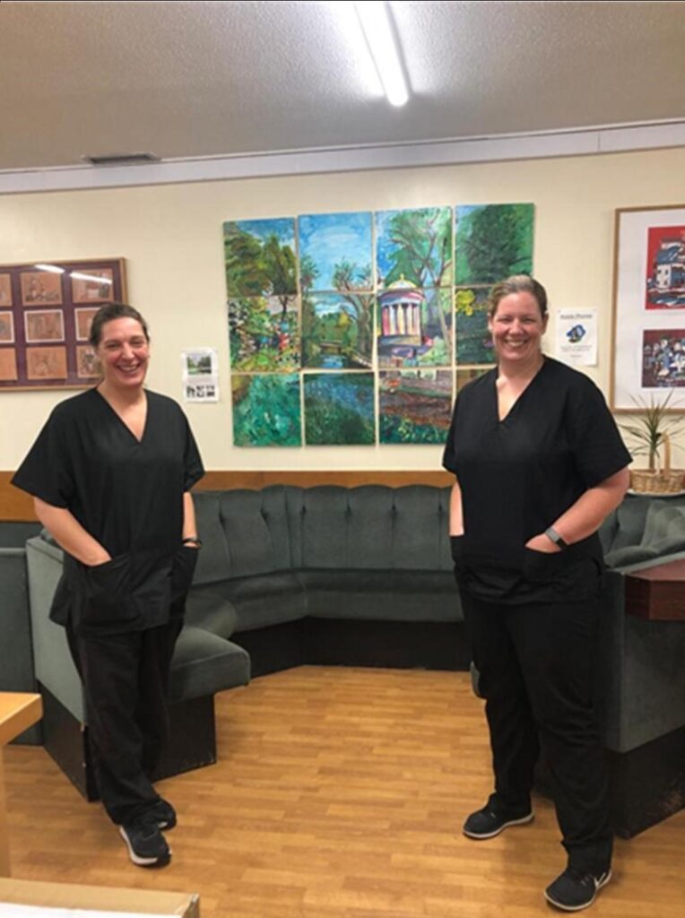 Two female nurses standing in waiting room area.