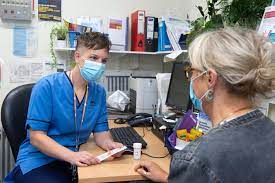 Nurse sitting at desk in discussion with patient.