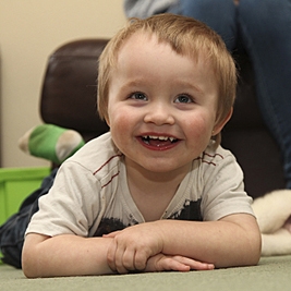 Young boy with crossed arms smiling on carpet