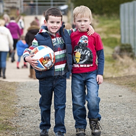 Two young boys arm in arm with one holding a football