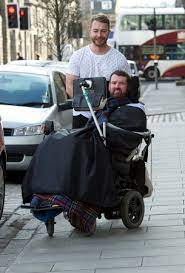 man assisting another man in wheel chair