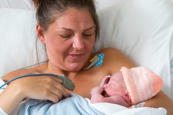A woman and her newborn baby in a hospital post delivery suite