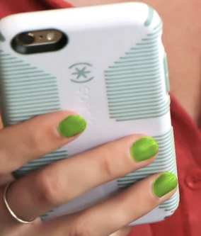 Close up of hand with green fingernails holding mobile phone