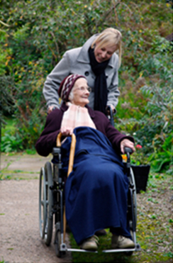 Woman pushing older woman in wheelchair