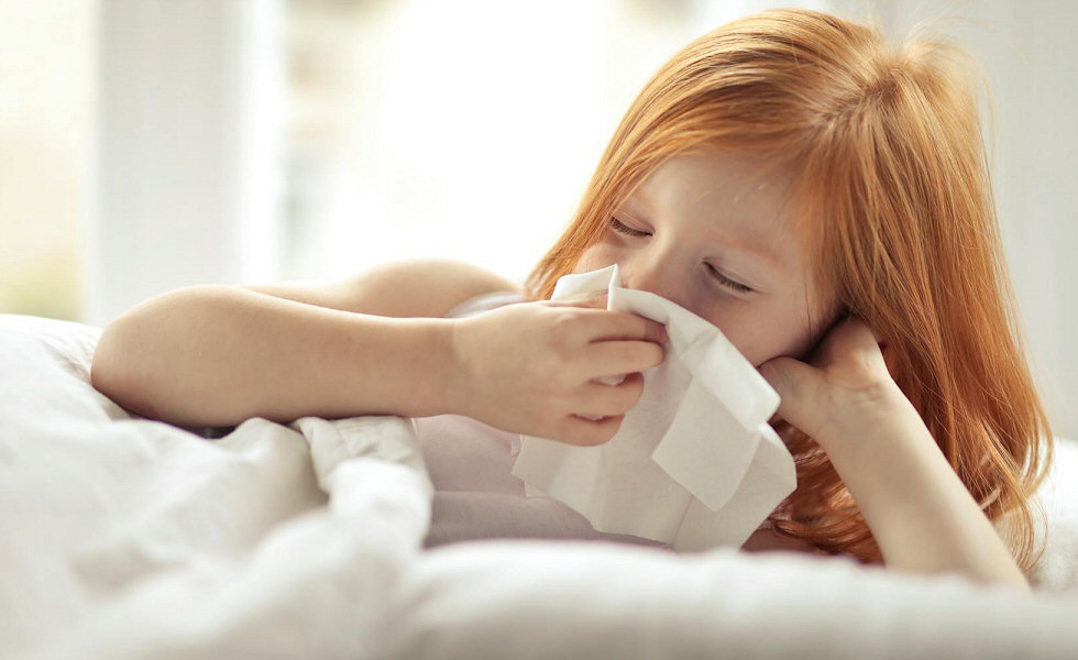 a young girl with red hair blowing her nose on a tissue