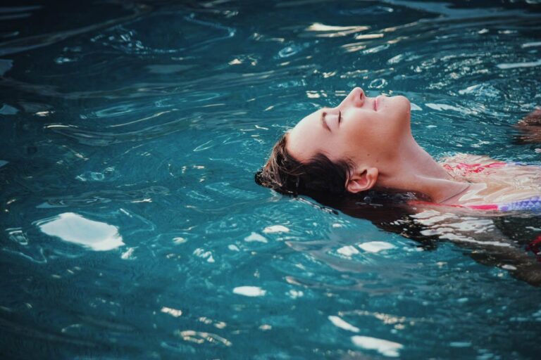 A female doing a leisurely backstroke in blue water