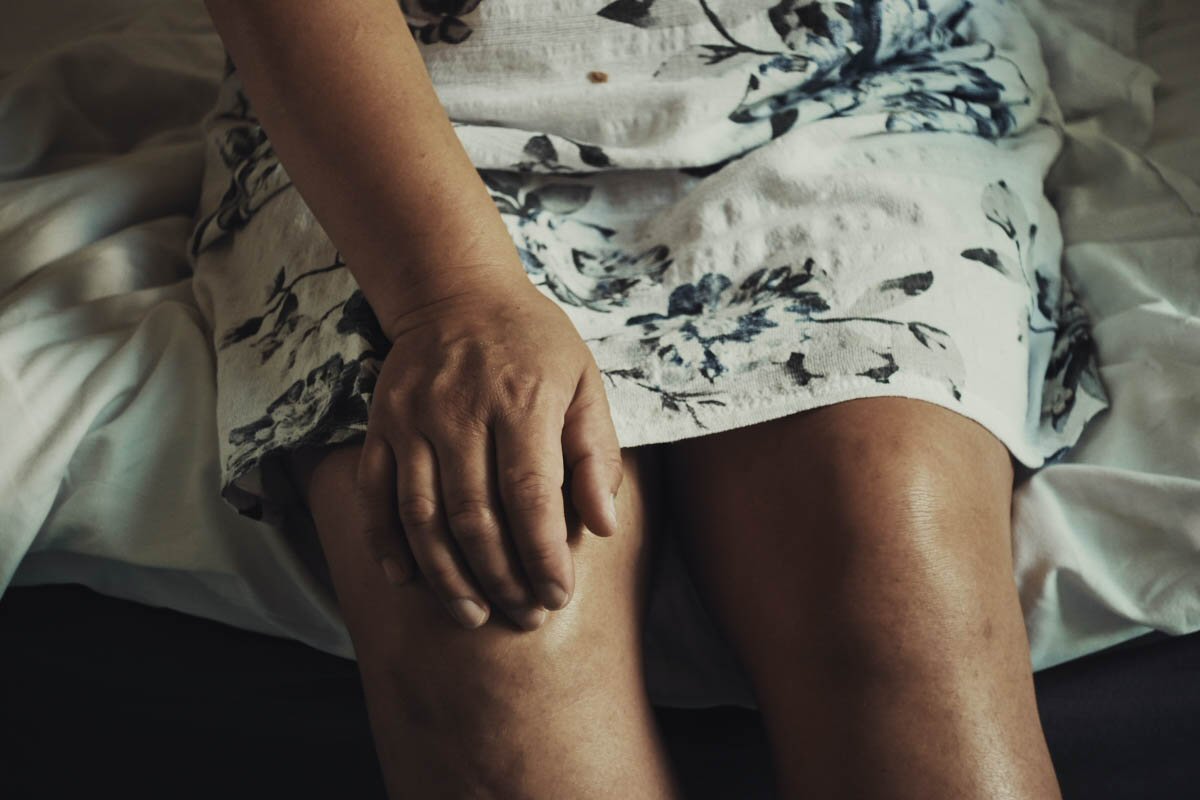 Close up of a woman's knees, her hand on the right knee