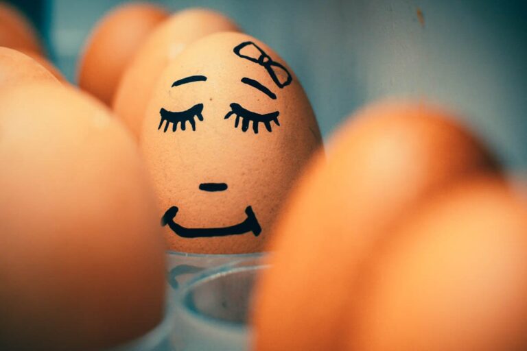Eggs in a fridge. One of the eggs has a face drawn on it in black felt pen