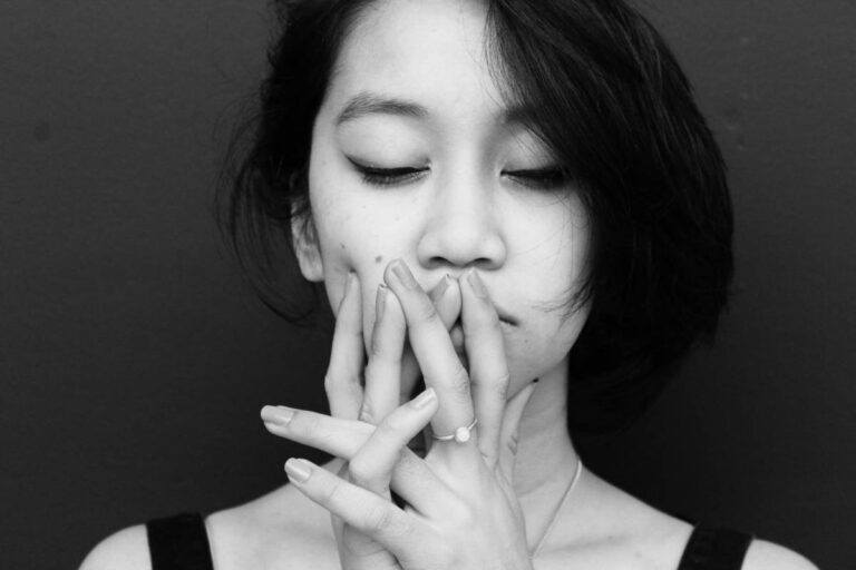 A young female holing her hands to her face, looking thoughtful or pensive