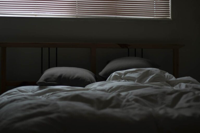 An unmade bed in the semi-dark