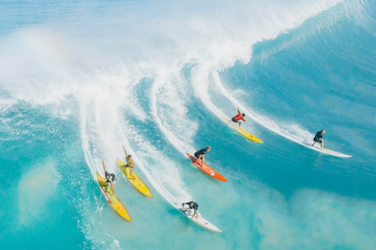 Six surfers riding the waves in a blue sea