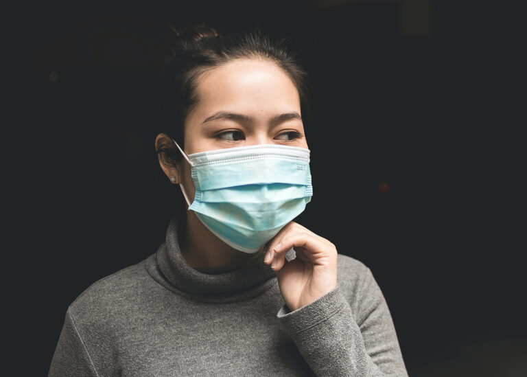 A woman wearing a blue COVID-19 PPE mask