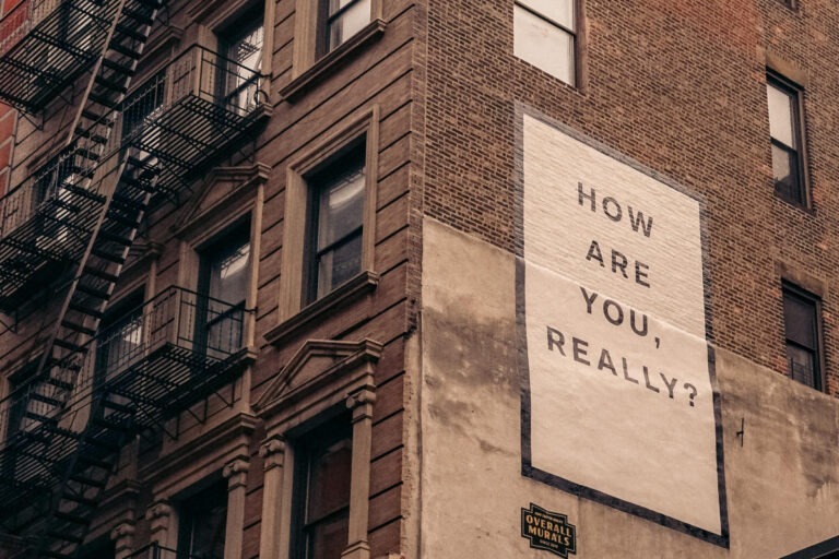 Side of a building with a billboard saying "How Are You Really??"